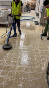 Workers from All American Carpet & Tile cleaning a commercial tiled floor with a scrubber in San Diego, CA