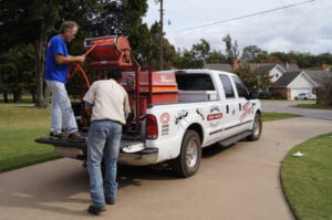 Two Reliable Termite of OKC workers preparing equipment on the back of a pest control truck in Oklahoma City, OK.