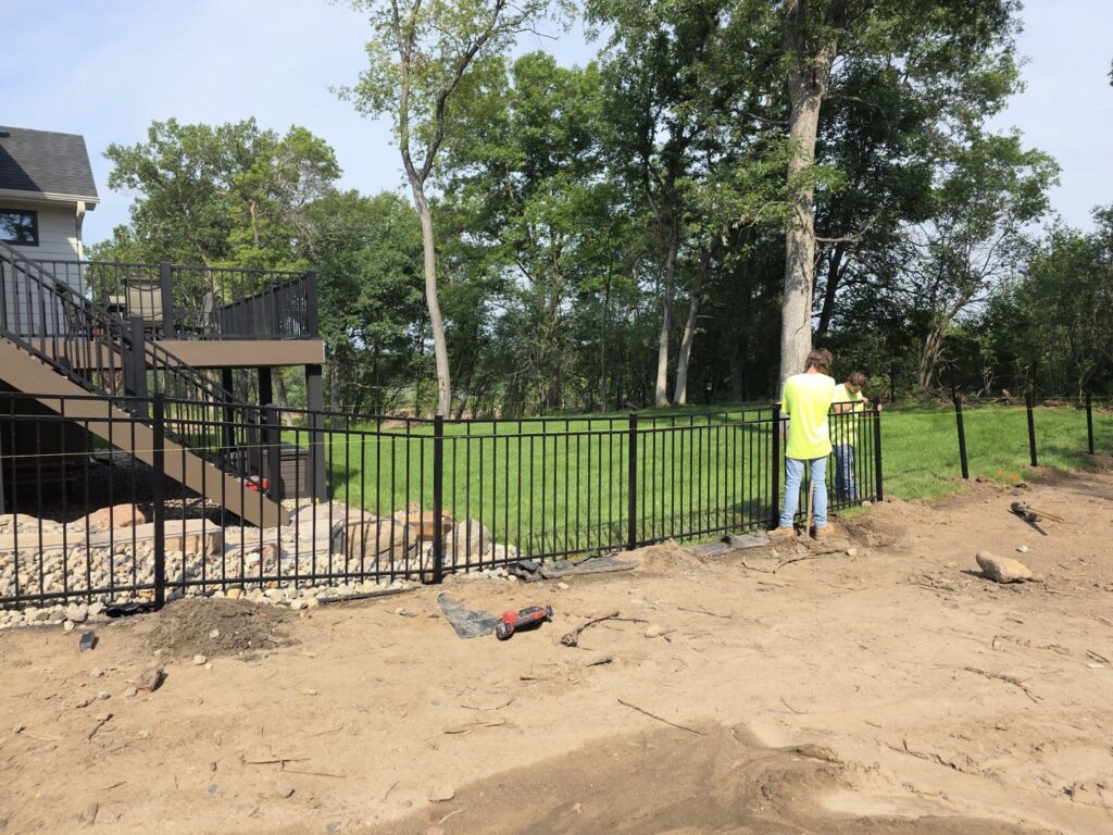 Workers installing a black aluminum fence around a residential deck by MN Mike's Fence and Repair in Lakeville, MN.