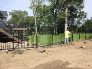 Workers installing a black aluminum fence around a residential deck by MN Mike's Fence and Repair in Lakeville, MN.