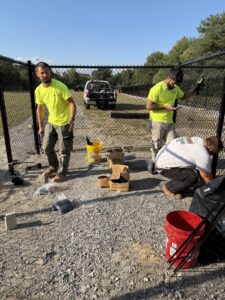 Workers installing a black chain-link fence for a client of Premier Fence LLC in Canton, MA.
