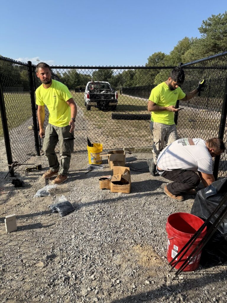 Workers installing a black chain-link fence for a client of Premier Fence LLC in Canton, MA.