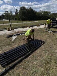 Workers installing a black metal fence, preparing posts on site for Premier Fence LLC in Canton, MA.