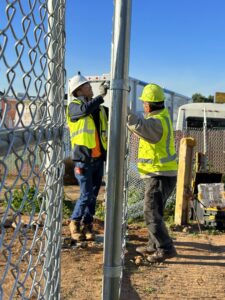 Two workers installing a chain-link fence, demonstrating the expertise of San Diego Fencing Contractor A's Pro Build Fencing in San Diego, CA.