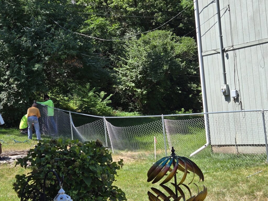 Workers installing a new chain-link fence, demonstrating services by Sergio's Fence in Kansas City, KS.