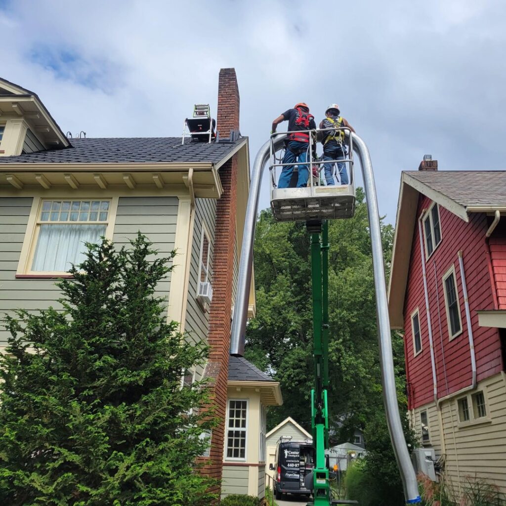 Two workers in a lift bucket installing a flexible chimney liner into a residential chimney by Century Chimney Sweep and Repair in Cleveland, OH