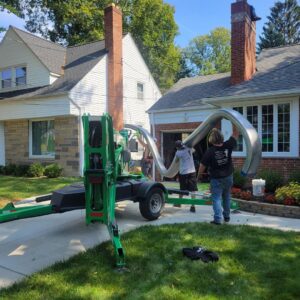Workers installing a large flexible chimney liner into a chimney using a lift bucket by Century Chimney Sweep and Repair in Cleveland, OH