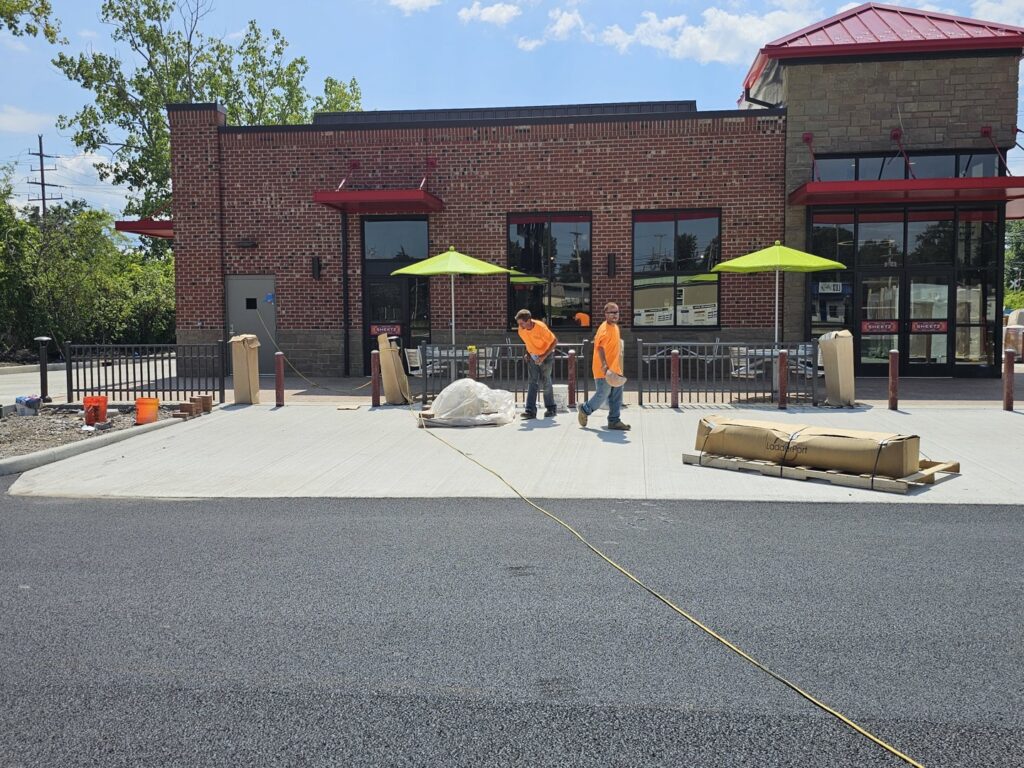 Workers on site installing a commercial black metal fence for Affordable Fence Builders in Dayton, OH.