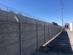 Workers installing concrete fence panels on a sloped residential property for StackWall Manufacturing in Pomona, CA.