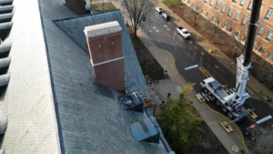 Workers installing lightning rods on a commercial building roof with a crane for Midwest Lightning Rods, LLC in Decatur, IL.