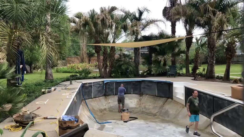 Two workers installing a new liner in an empty pool, with equipment around, demonstrating service by Brian's Pool Service in Baton Rouge, LA.