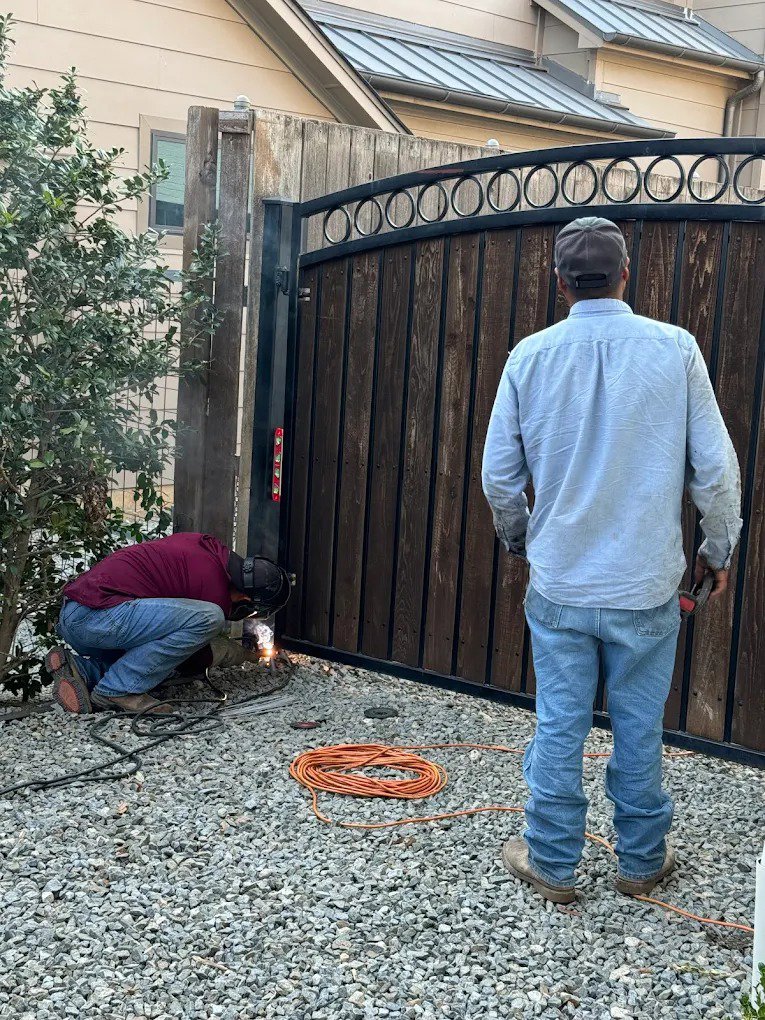 Two workers installing and welding a wooden and metal gate, a service by HDR Systems Gate, Fence & Garage doors in Plano, TX