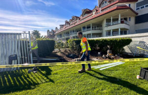 Two workers installing a white metal fence with caution tape, a project by San Diego Fencing Contractor A's Pro Build Fencing in San Diego, CA.