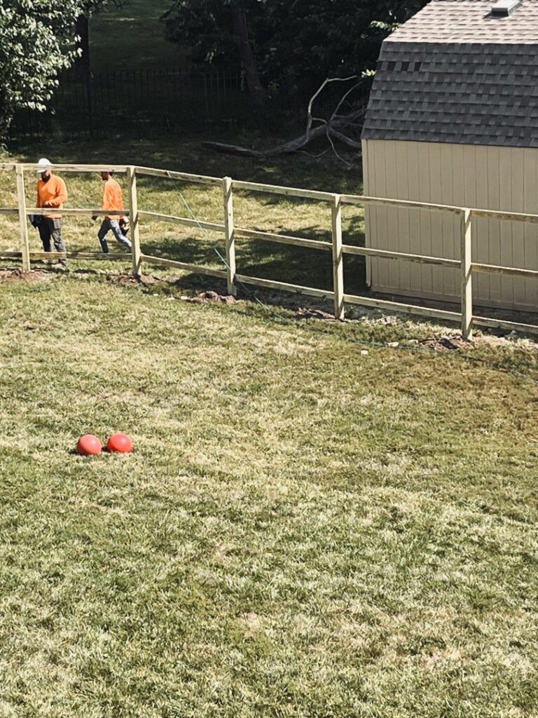 Two workers installing the wooden frame for a new fence, showcasing work by Sergio's Fence in Kansas City, KS.