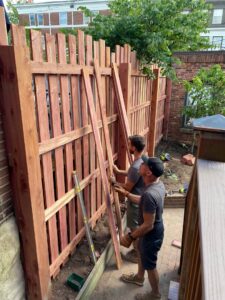 Two workers installing wood fence pickets for a new fence by Sexton Property Services STL in High Ridge, MO.