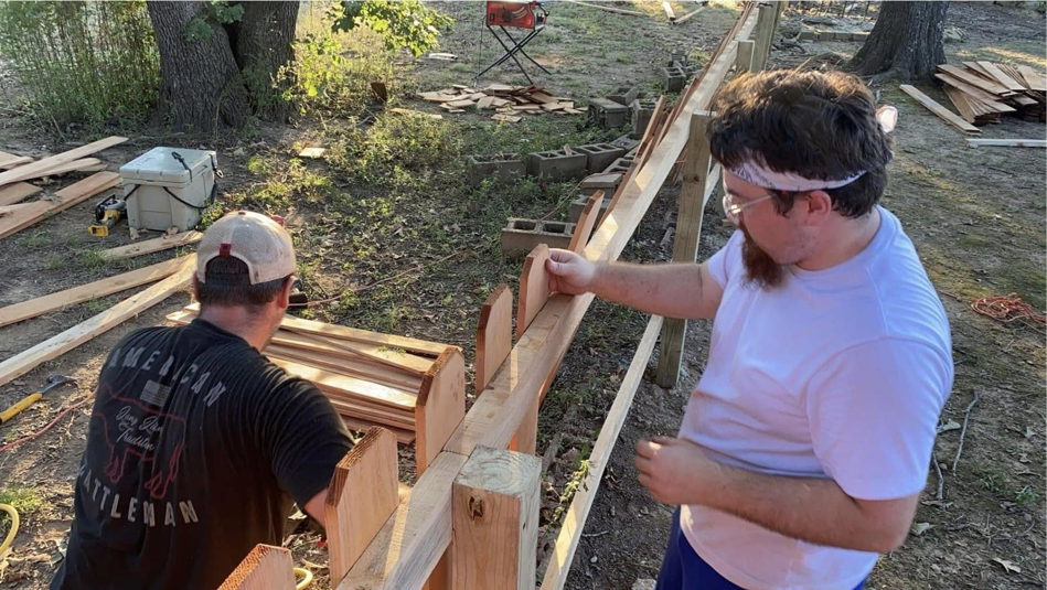 Two workers installing wooden pickets on a new fence project for Fianna Fencing Company in Fort Smith, AR.