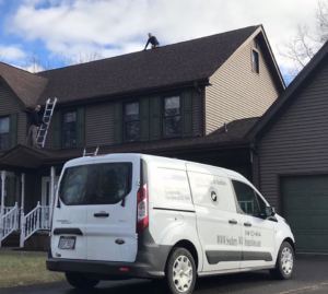 Workers on a roof with a Hibbs Inspections and Pest Control van parked outside in Beckley, WV