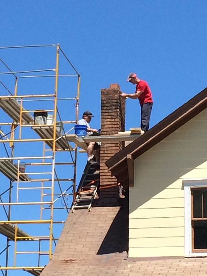 Two workers on scaffolding performing masonry repair work on a residential chimney for The Chimney Doctor in Louisville, KY.