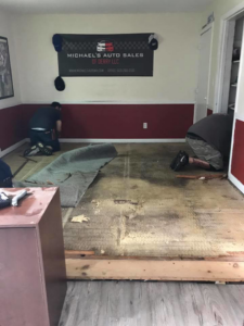 Workers removing old carpet and flooring to prepare a subfloor for new installation by The Vaira Companies, LLC in Londonderry, NH.