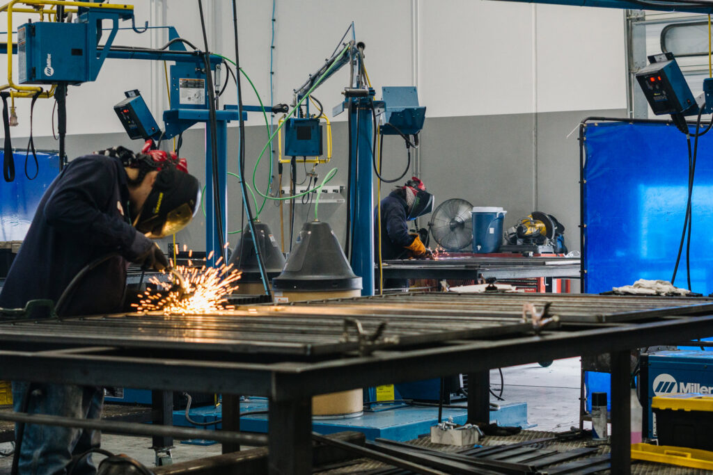 Workers welding metal frames in the fabrication shop at Hirschi Iron, a fencing contractor in North Las Vegas, NV.