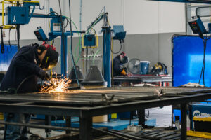 Workers welding metal frames in the fabrication shop at Hirschi Iron, a fencing contractor in North Las Vegas, NV.