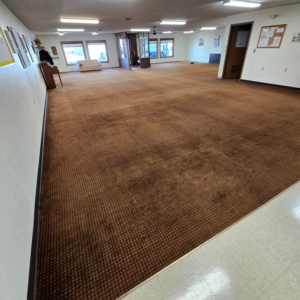 Worn brown commercial carpet in a large room, ready for replacement by LaValle Flooring Inc - Jamestown, ND