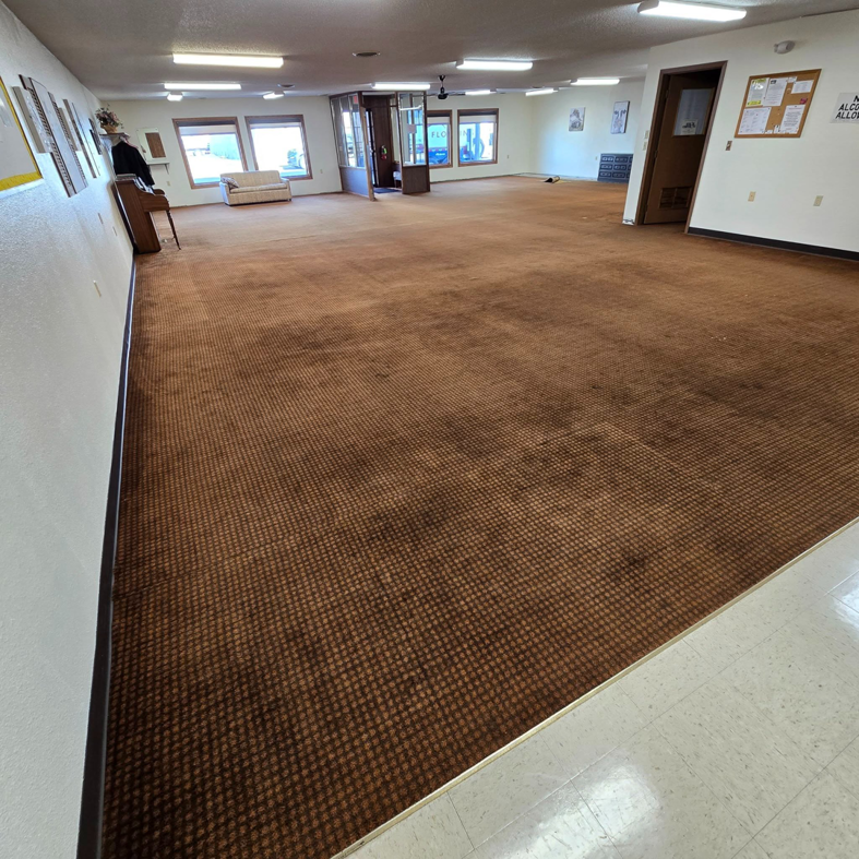 Worn brown commercial carpet in a large room, ready for replacement by LaValle Flooring Inc - Jamestown, ND