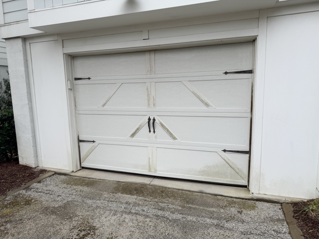 A worn white garage door showing signs of age, ready for service by On Track Garage Doors in Charleston, SC.