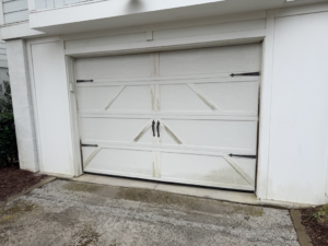 A worn white garage door showing signs of age, ready for service by On Track Garage Doors in Charleston, SC.