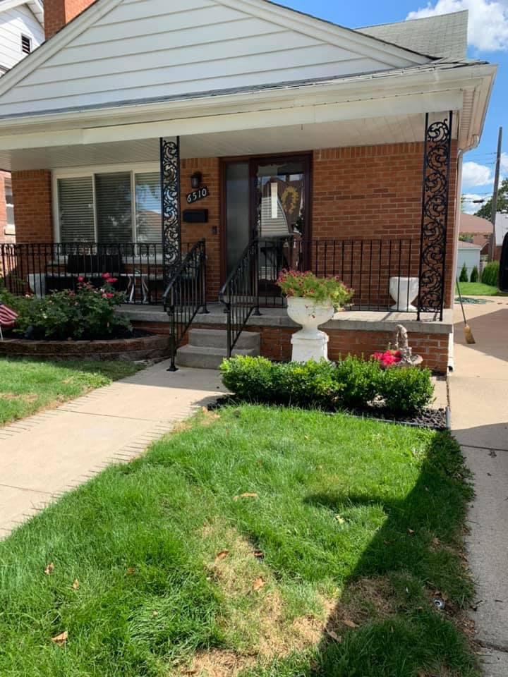 A beautiful wrought iron porch railing and low fence installed by Ideal Wrought Iron in Detroit, MI