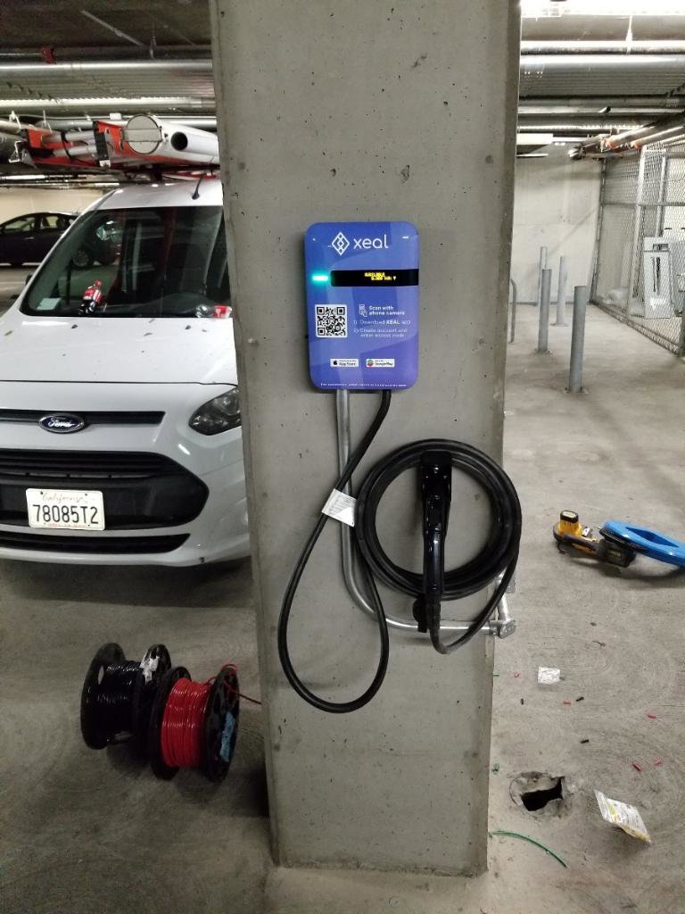 A Xeal electric vehicle charger installed on a concrete pillar in a parking garage by Wisdom Electrical in San Francisco, CA.