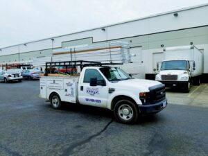 An Xpress Doors LLC service truck loaded with garage door panels, parked at a commercial job site in Salem, OR