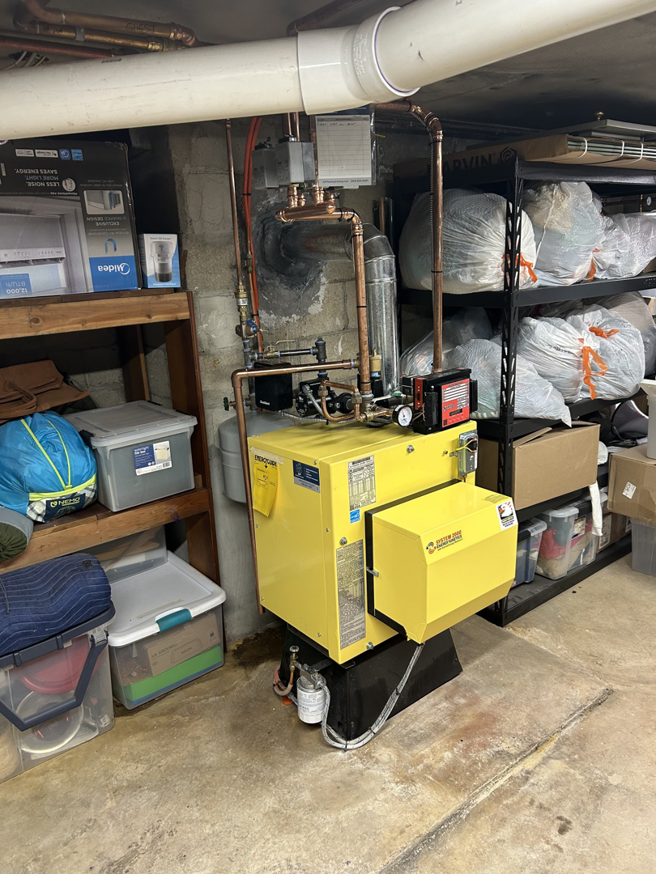 A yellow boiler heating system with copper pipes in a basement by JLP Heating & Cooling in Norwalk, CT