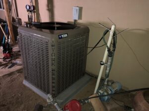 An outdoor York AC condenser unit undergoing maintenance or installation with tools and pipes by Hellerud Air in Peoria, AZ.