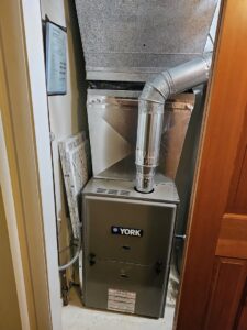 A new York furnace unit and ductwork expertly installed in a utility closet by Perfect Temp LLC in Bozeman, MT.