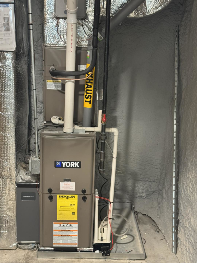 An indoor York HVAC furnace system with exhaust piping and ductwork installed by D and C Mechanical, Inc. in Tewksbury, MA.