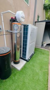 A York brand mini-split style outdoor HVAC unit installed alongside a water softener system by Pelican Heating and Air in Carlsbad, CA.