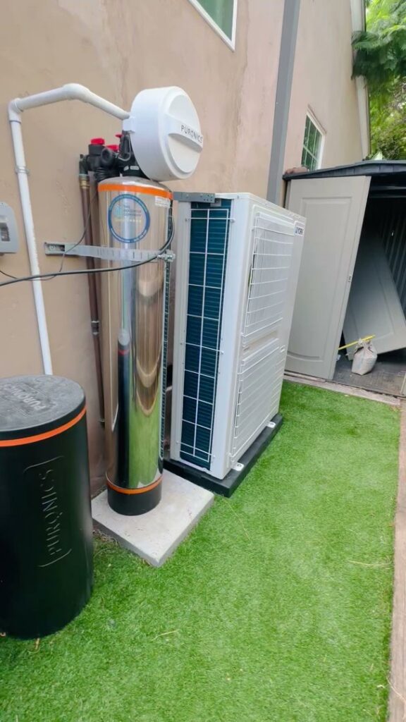 A York brand mini-split style outdoor HVAC unit installed alongside a water softener system by Pelican Heating and Air in Carlsbad, CA.