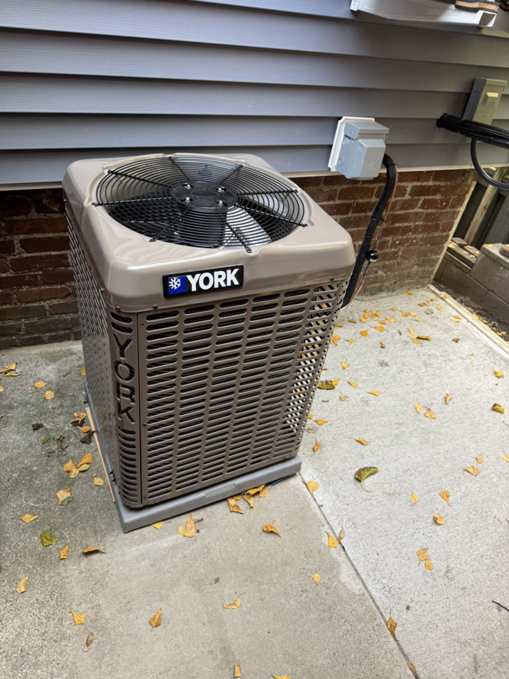 A new York outdoor HVAC condenser unit installed next to a building by D and C Mechanical, Inc. in Tewksbury, MA.