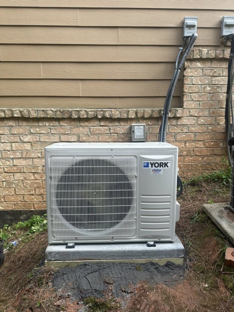 A new YORK outdoor HVAC unit installed next to a residential building by Delta Heating, Cooling, Plumbing in Wilson, NC.