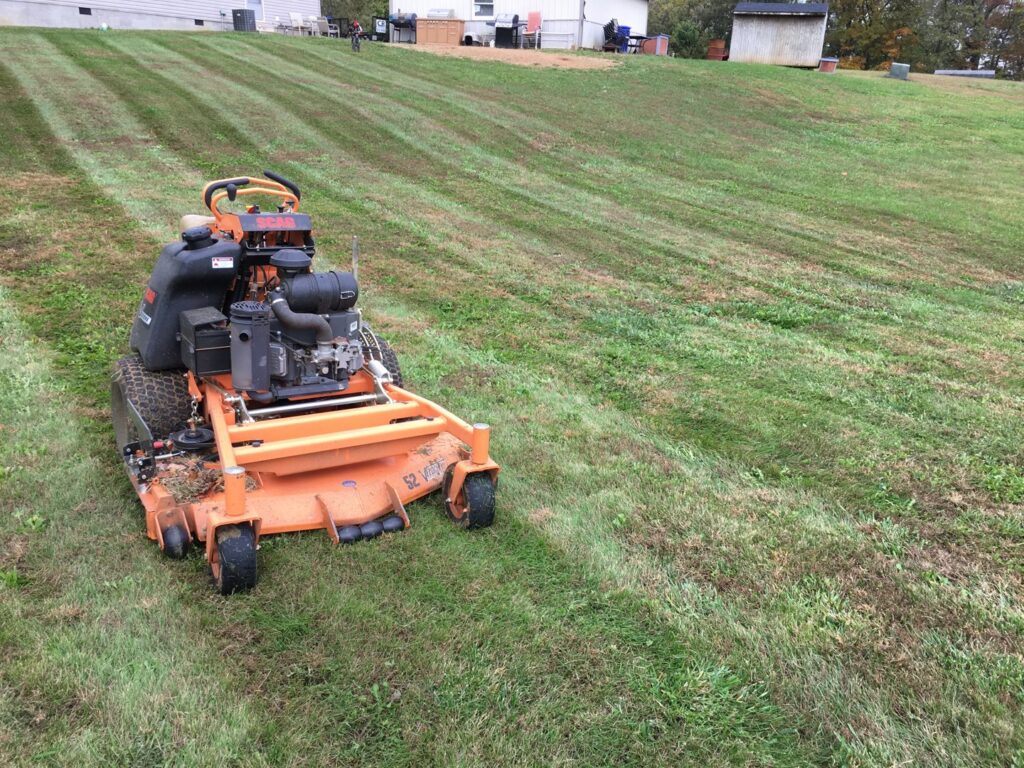 An orange zero-turn mower on a freshly striped lawn, showcasing professional lawn care by C&R Lawn Care and Property Services in Evansville, IN.