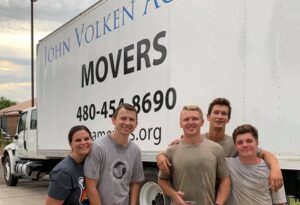 The Academy Movers team posing with a family in front of their branded moving truck in Gilbert, AZ.