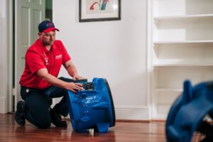 A Rainbow Restoration of Meridian technician adjusting a professional air mover to dry a water-damaged floor in Meridian, ID.