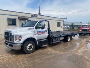 Adkison Towing flatbed truck towing another truck, demonstrating their heavy-duty capabilities in Jacksonville, FL.