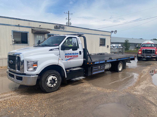 Adkison Towing flatbed truck towing another truck, demonstrating their heavy-duty capabilities in Jacksonville, FL.