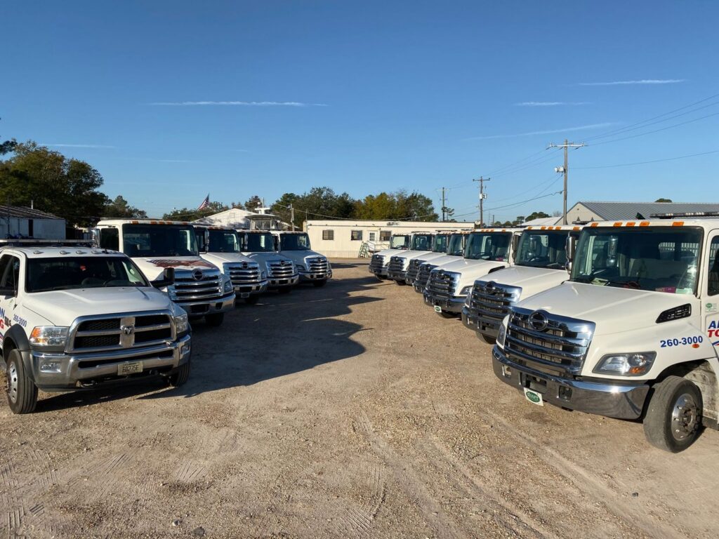 A line of Adkison Towing flatbed trucks parked at their lot, ready for service in Jacksonville, FL.