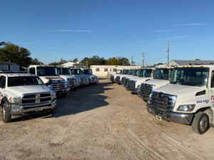 A line of Adkison Towing flatbed trucks parked at their lot, ready for service in Jacksonville, FL.