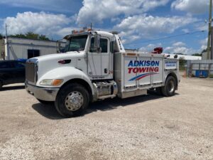 A white Adkison Towing wrecker truck parked on a sunny day, ready for service in Jacksonville, FL.