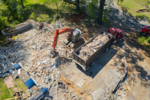 Aerial shot of an excavator efficiently loading demolition debris into a large dump truck for Nuckles Services in Birmingham, AL