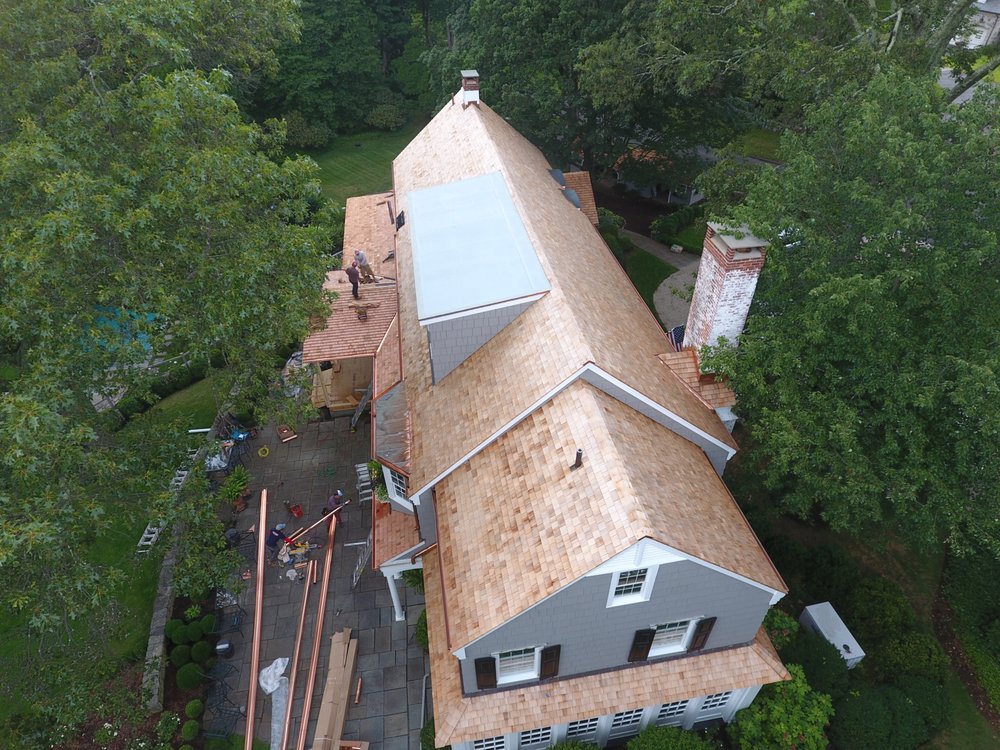 Aerial view of a large residential property showcasing gray shingle siding and cedar shake roofing by JM Roofing & Siding in Rogers, AR.